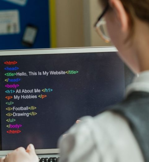 Over the shoulder shot of a female high school student doing computer coding on a laptop.